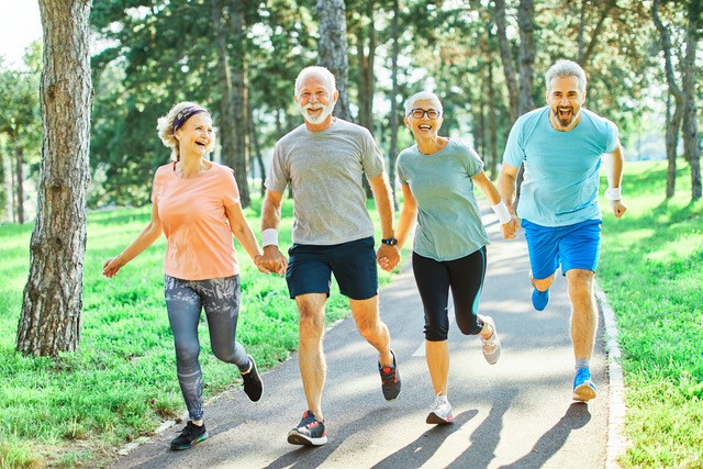 happy group of 4 people running together while holding hands