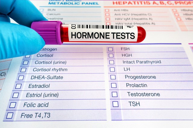 Gloved finger holding blood tube for hormone tests