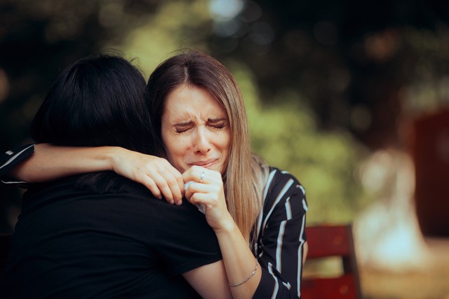 Woman hugging another in forgiveness