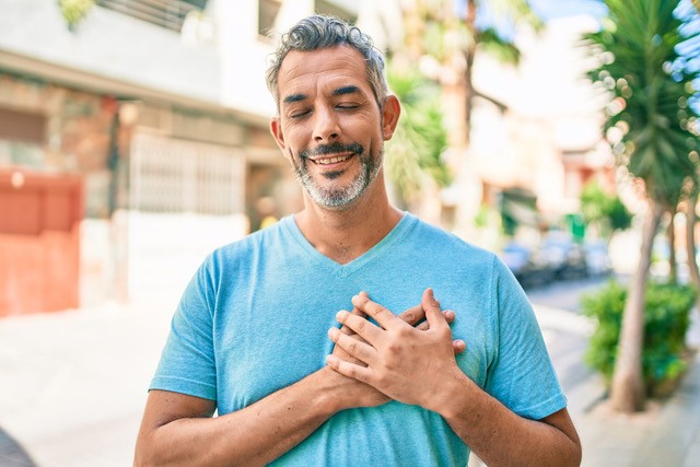 smiling, thankful man with hands on heart