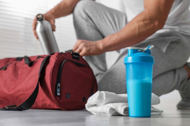 Man packing workout bag with nutritional shake