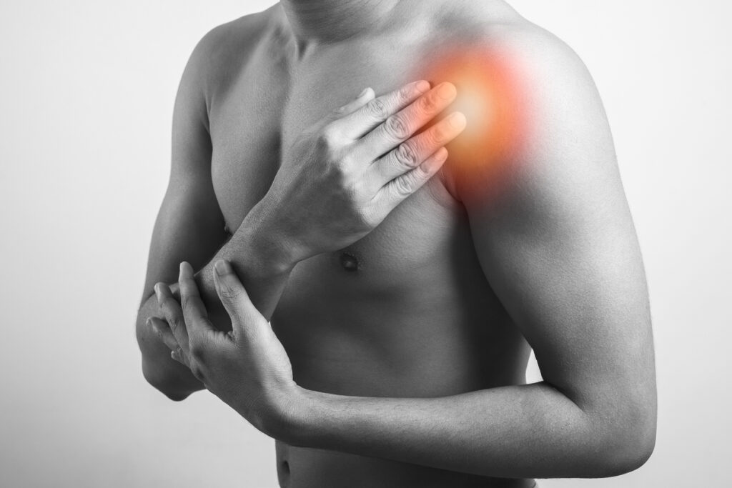 fitness Man clutching shoulder deltoids injury with pain highlighted in red glow isolated in grey background.